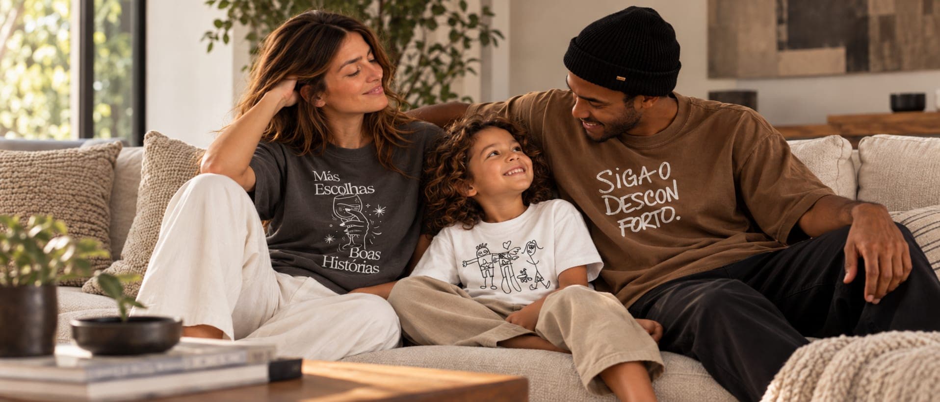 Família sentada no sofá usando camisetas Torto: mãe, filho e pai sorrindo